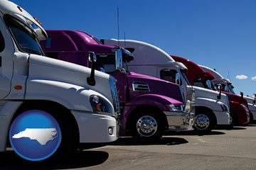row of semi trucks at a truck dealership - with North Carolina icon