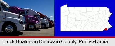 row of semi trucks at a truck dealership; Delaware County highlighted in red on a map