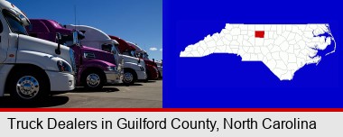 row of semi trucks at a truck dealership; Guilford County highlighted in red on a map
