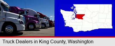 row of semi trucks at a truck dealership; King County highlighted in red on a map